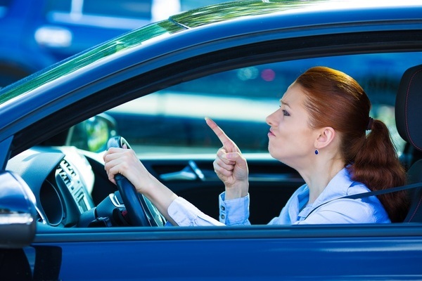 Angry woman driver pointing ahead in blue car-1