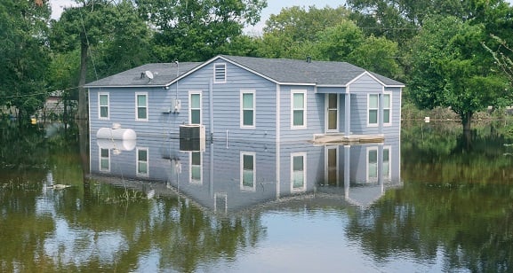 gray rancher type home surrounded by flood water