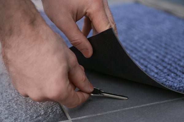 Hands putting key under door mat