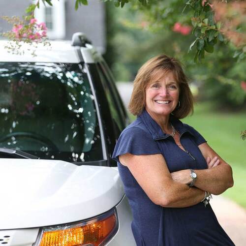 middle age woman smiling and leaning on car