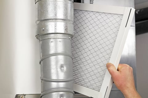 human hand holding disposable HVAC filter by HVAC venting