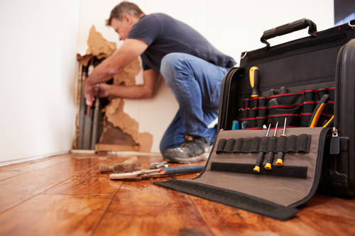 repair man working in house plumbing in wall