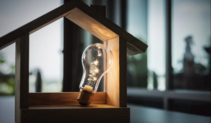 Wood frame house model with light bulb home electric concept