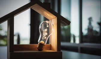 Wood frame house model with light bulb home electric concept