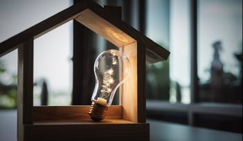 Wood frame house model with light bulb home electric concept